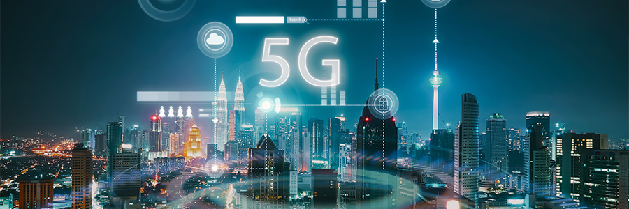 A futuristic cityscape at night with skyscrapers lit up. A prominent "5G" holographic text floats above the skyline, surrounded by digital icons and lines symbolizing connectivity. The scene conveys advanced technology and urban development.